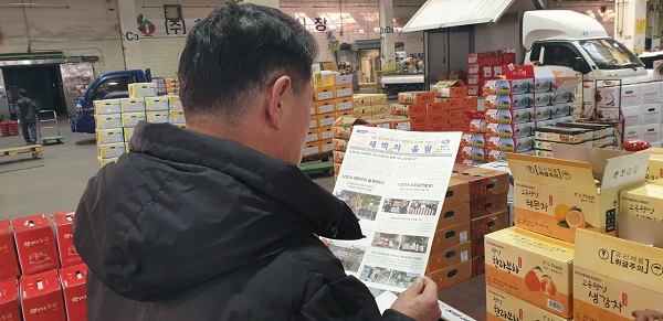 사진=소식지를 읽고 있는 농산물도매시장 종사자