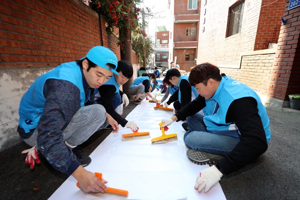 15일 서울 마포구에서 대우건설 직원들이 노후주택에 도배할 벽지에 풀을 바르고 있다. 사진=대우건설