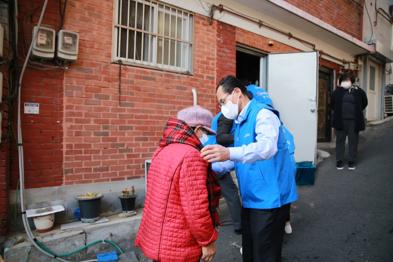 지난 29일 창신 2동 김장김치 전달 행사에서 김정기 우리카드 대표이사(오른쪽)가 주민에게 목도리를 걸어주고 있다. 사진=우리카드 제공